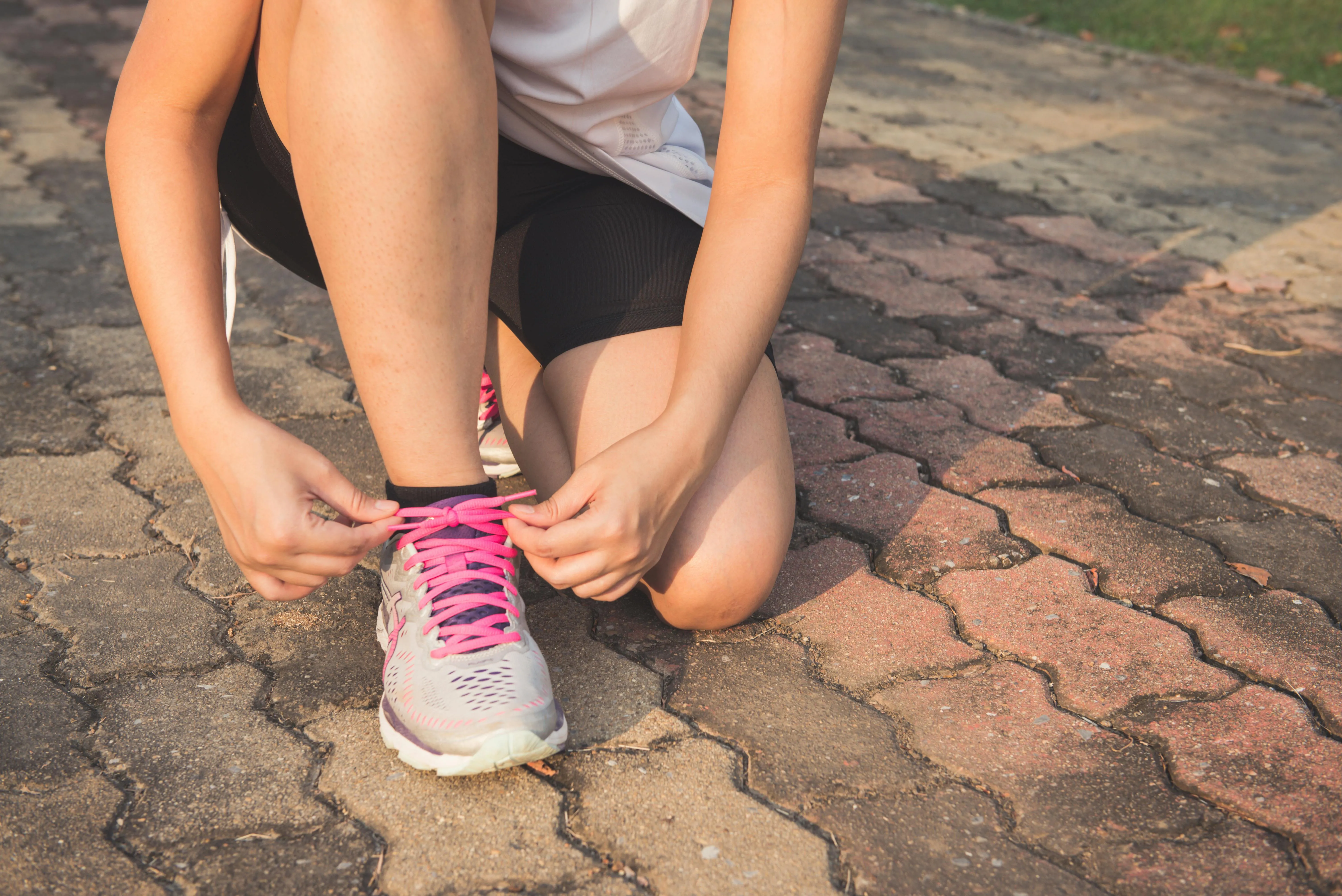 Sportive nouant ses lacets de running sur un chemin